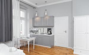 a kitchen with gray cabinets and a table with chairs at Loft Rooms - Classic Apartments Location, bezpłatny parking in Ełk