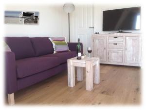sala de estar con sofá púrpura y mesa en Loft 270° im Kapitänshaus Wangerooge, en Wangerooge