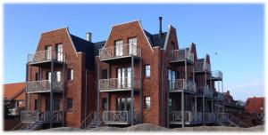 - un bâtiment en briques avec des balcons sur le côté dans l'établissement Loft 270° im Kapitänshaus Wangerooge, à Wangerooge