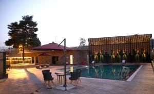 a pool with chairs and a table next to a building at The Fern Residency Udaipur in Udaipur