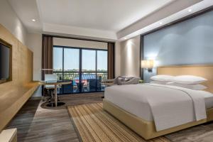 a bedroom with a bed and a desk and a large window at Courtyard by Marriott Siem Reap Resort in Siem Reap