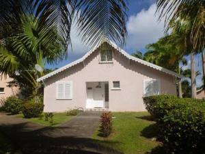 una pequeña casa blanca con una palmera en Villa Laurencin, en Sainte-Rose