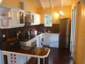 a kitchen with white cabinets and a refrigerator at Villa Laurencin in Sainte-Rose