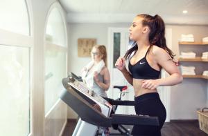 a woman is running on a treadmill in a gym at Château L'Hospitalet Wine Resort Beach & Spa in Narbonne