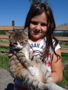 Ein junges Mädchen hält eine Katze in der Unterkunft Farma Růžová in Růžová