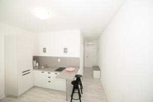 een witte keuken met een aanrecht en een kruk bij Guest House Arsenal Accommodation in Zadar