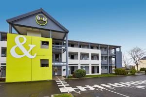 un edificio con un letrero amarillo en un estacionamiento en B&B HOTEL AVRANCHES Baie du Mont St-Michel en Le Val-Saint-Père