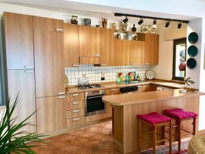 una cocina con armarios de madera y una barra con taburetes en BellaVista Apartments, en Taormina