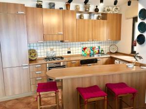 una cocina con armarios de madera y taburetes acolchados de color rosa en BellaVista Apartments, en Taormina