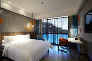 棉兰ibis Styles Medan Pattimura的一间卧室，配有一张床、一张书桌和一扇大窗户