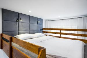 a bedroom with a wooden bed with white sheets at Apartament Felicjanek in Krakow