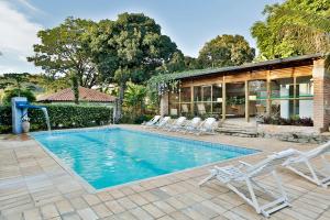 a swimming pool with chairs and a house at Solar dos Ipês in Serra do Cipo