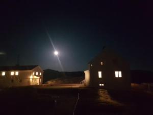 un clair de lune brille sur deux maisons la nuit dans l'établissement Utsira Overnatting - Fyrvokterboliger, à Utsira