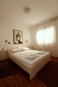 a large white bed in a bedroom with a window at Apartment Draga 17 in Njivice