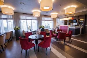 a restaurant with red chairs and tables and windows at Respublika Apart-hotel in Cheboksary