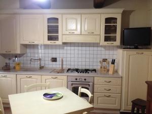 a kitchen with white cabinets and a table and a tv at Toscana Relax Gambassi Terme in Gambassi Terme