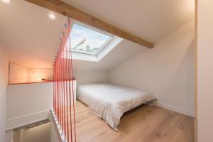 a small attic bedroom with a bed and a window at F2 chambre en duplex (calme) plein centre ville 1 min de la plage in Saint-Raphaël