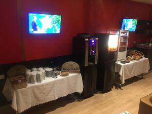 a room with two tables and a tv on a wall at Le Grand Hotel in Maubeuge