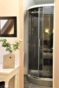 a glass shower in a bathroom with a table at Logis L'Ecu De France in Mauriac