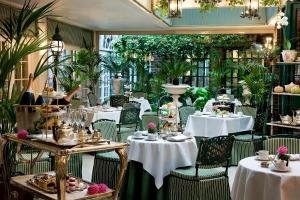 un restaurante con mesas blancas, sillas y plantas en The Chesterfield Mayfair en Londres