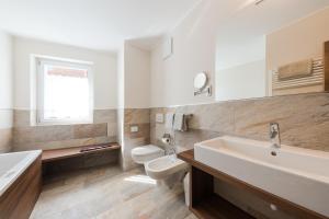 Baño blanco con aseo y lavamanos en Residence Gruberhof en Schenna