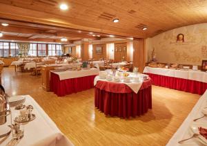 a dining room with tables with red and white table settings at Hotel Restaurant Lindenhof in Bräunlingen