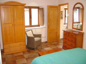 a bedroom with a bed and a dresser and a chair at Stone Cottage O CEBREIRO in Curtis
