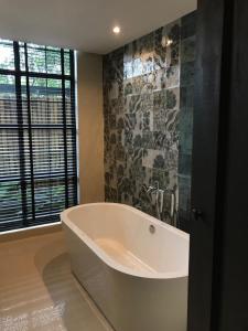 a bath tub in a bathroom with a window at Gajib Bed&Breakfast in Amphawa