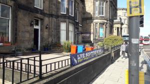 un cartello su una recinzione di fronte a un edificio di The Guards Hotel a Edimburgo