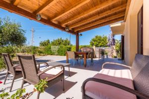 a patio with chairs and a table and a wooden pergola at B&B Le Dune - Self Check in in Lascari