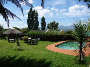 Leribe的住宿－Aloes Lodge，一个带桌椅的花园和一个游泳池