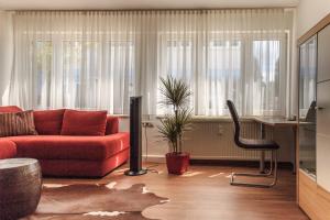ein Wohnzimmer mit einem roten Sofa und einem Stuhl in der Unterkunft Haus Pia Executive Apartments in Friedrichshafen