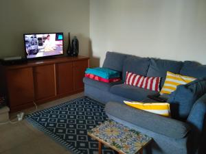 a living room with a blue couch and a tv at Rua 5 House in Gafanha da Vagueira