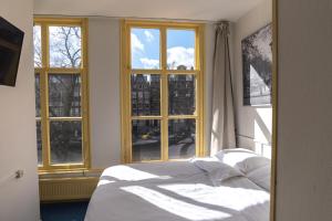 a bedroom with a bed in front of windows at Hotel Hoksbergen in Amsterdam