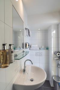 Baño blanco con lavabo y espejo en Hotel Hoksbergen, en Ámsterdam