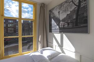 アムステルダムにあるHotel Hoksbergenの窓、ベッド、テレビが備わるベッドルーム1室が備わります。