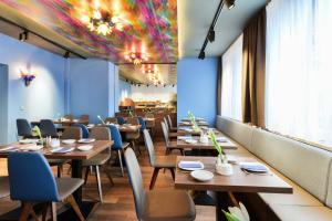 een restaurant met houten tafels en stoelen en een kleurrijk plafond bij Westend Hotel (non-smoking) in München