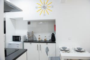 Una cocina con gabinetes blancos y un reloj en la pared. en Tropical house, en Sesimbra 4 fotos más