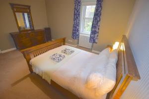 a bedroom with a wooden bed with white sheets at Lettermay House in Lochgoilhead