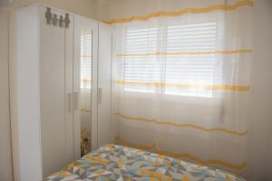 a bedroom with a bed and a window with curtains at Tropical house in Sesimbra