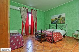 zieloną sypialnię z 2 łóżkami i stołem w obiekcie Casale Del Vento w mieście Aprilia