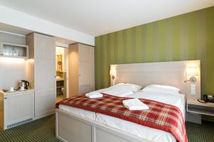 
a hotel room with a bed and a dresser at Ringhotel Warnemünder Hof in Warnemünde
