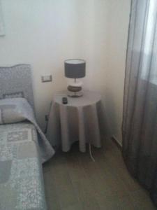 a small table with a lamp on it next to a bed at Marinella Guest House in Cornale