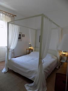 sypialnia z białym łóżkiem z baldachimem w obiekcie Casa Giglio w mieście Carloforte