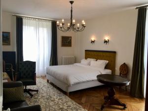ein Schlafzimmer mit einem Bett, einem Tisch und einem Kronleuchter in der Unterkunft Le Jardin Des Erables in Saint-Marcel