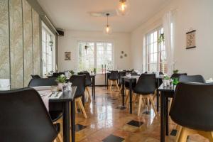 a dining room with tables and chairs and windows at Hotel - Restaurant De 4 Jaargetijden in Epen