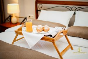 a tray with bread and a glass of orange juice on a bed at Ameri Apartments Tbilisi in Tbilisi City