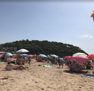 a group of people sitting on a beach with umbrellas at Cala Azul 304-306 Tamarit in Tamarit
