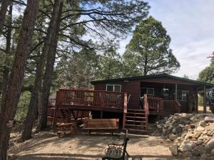a log cabin with a large deck and trees at Gonzales Cozy Little Bear Cabin in Ruidoso