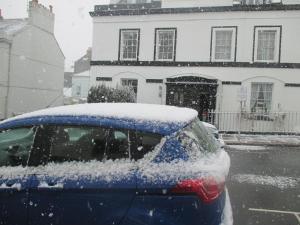 un coche cubierto de nieve frente a un edificio en Caledonia Guest House, en Plymouth